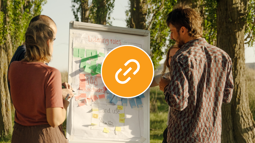 A team is gathered around a white board full of colourful post-it notes